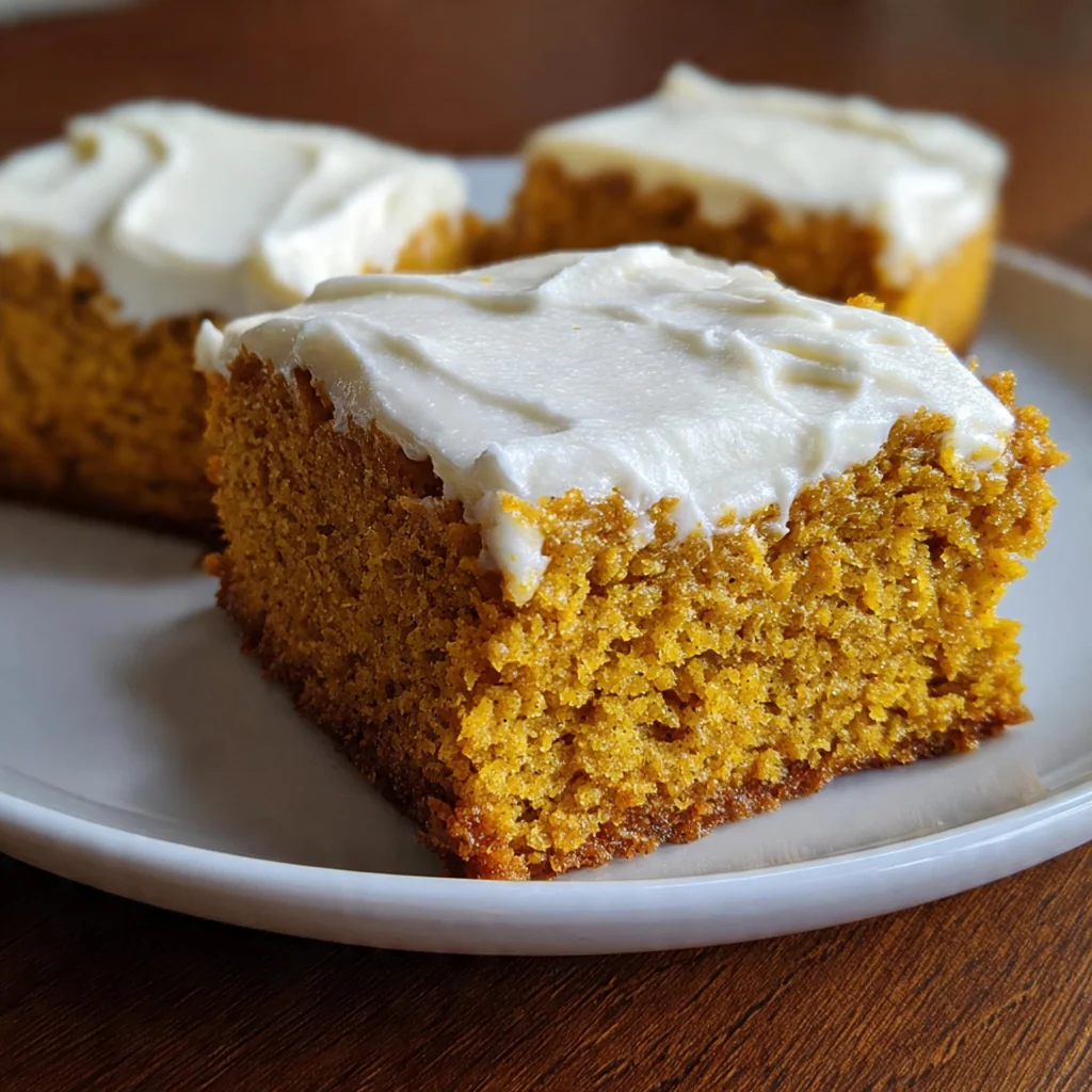 Close-up of a single square of moist pumpkin bar with a thick layer of velvety cream cheese frosting